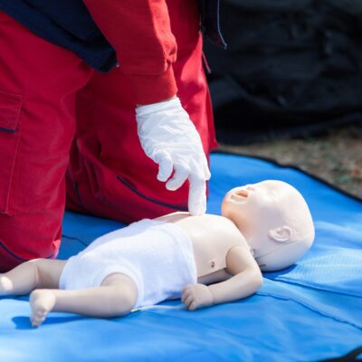 Paramedic performing CPR on baby dummy with two-finger chest compression